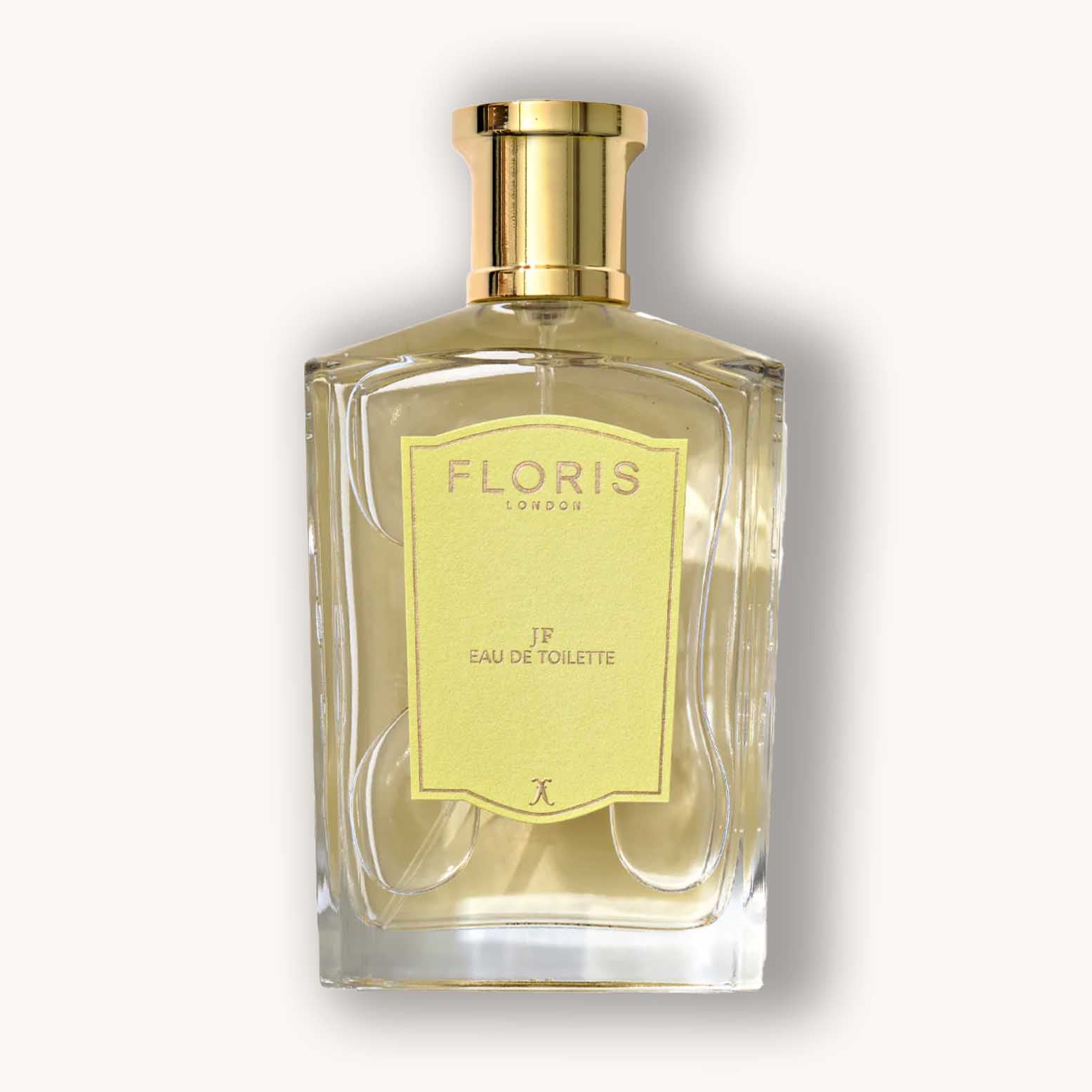 Alt text: A clear glass bottle of Floris London JF Eau de Toilette, showcasing a light yellow fragrance with an elegant gold cap and a stylish label.