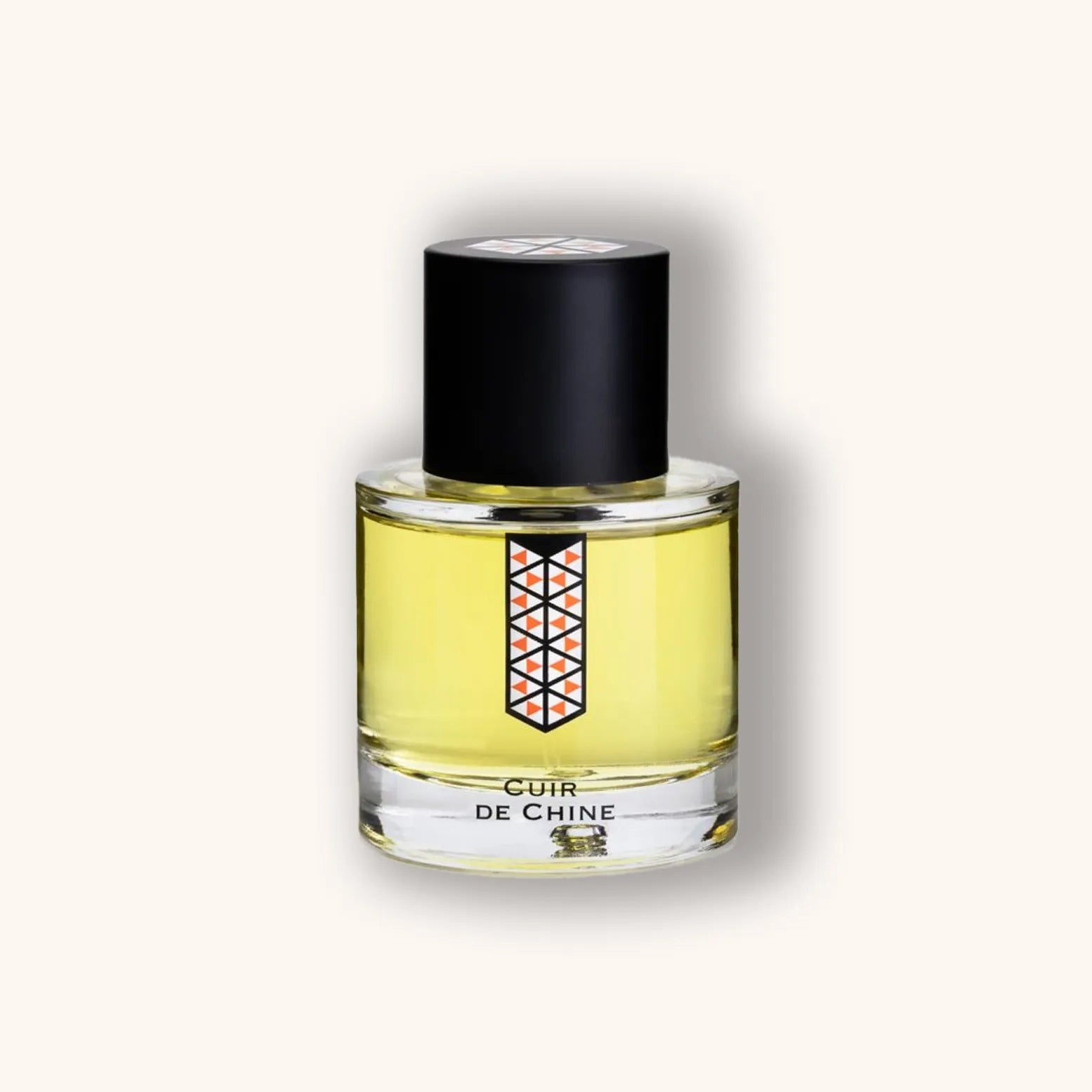 Ronde flacon van Les Indémodables Cuir de Chine met licht gele inhoud, zwarte dop en geometrisch oranje-zwart label.