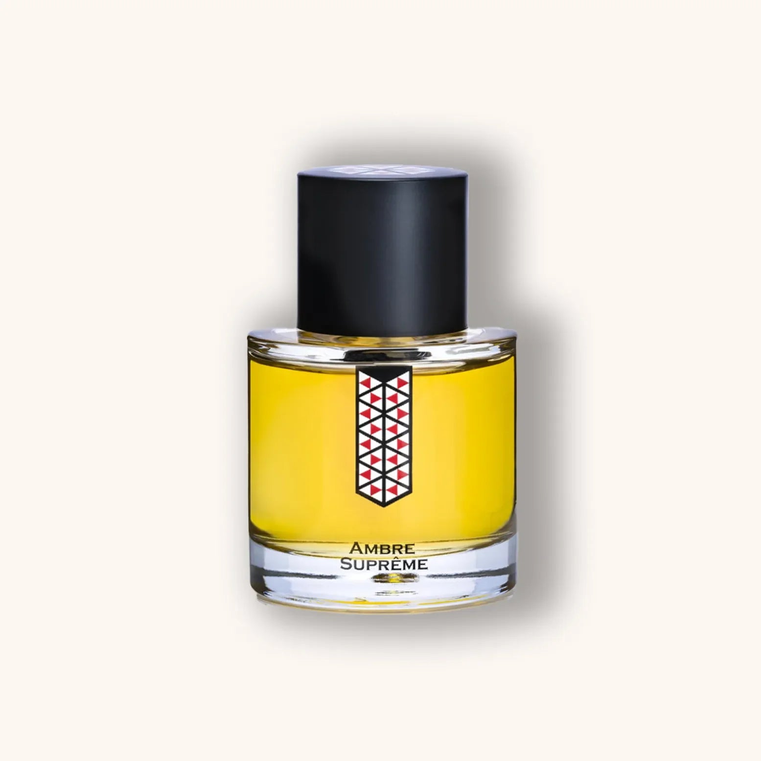 Ronde flacon van Les Indémodables Ambre Suprême met goudgele inhoud, zwarte dop en geometrisch rood-zwart label.