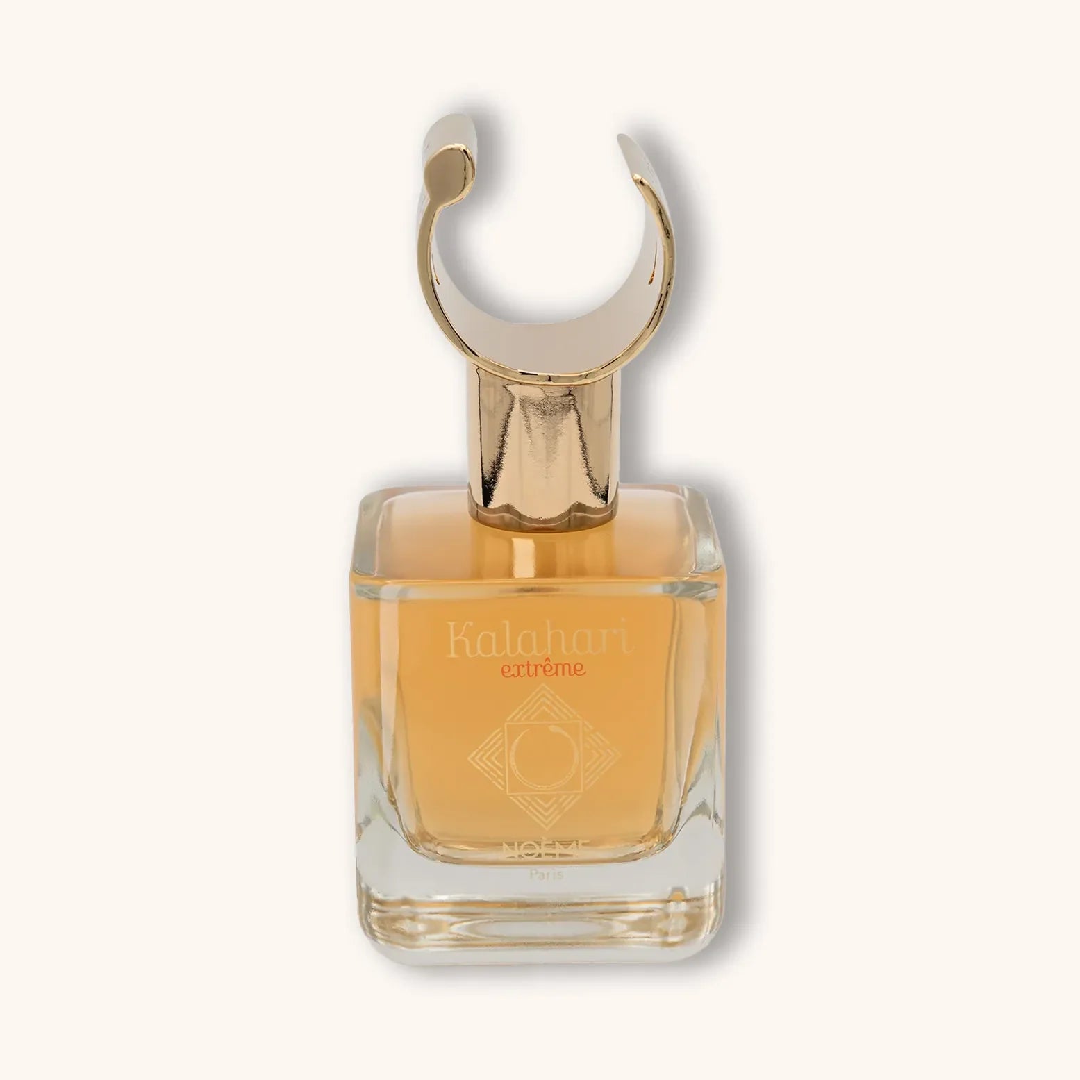 Alt text: A clear glass bottle of Noème Paris Kalahari Extreme perfume, featuring an elegant gold cap shaped like a crescent. The fragrance is a warm amber color, reflecting sophistication and allure.