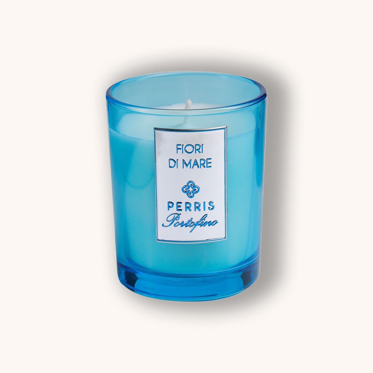 Alt text: A vibrant blue glass candle labeled "Perris Portofino Fiori di Mare," featuring a sleek white wax interior. The elegant design adds a touch of sophistication to any space.