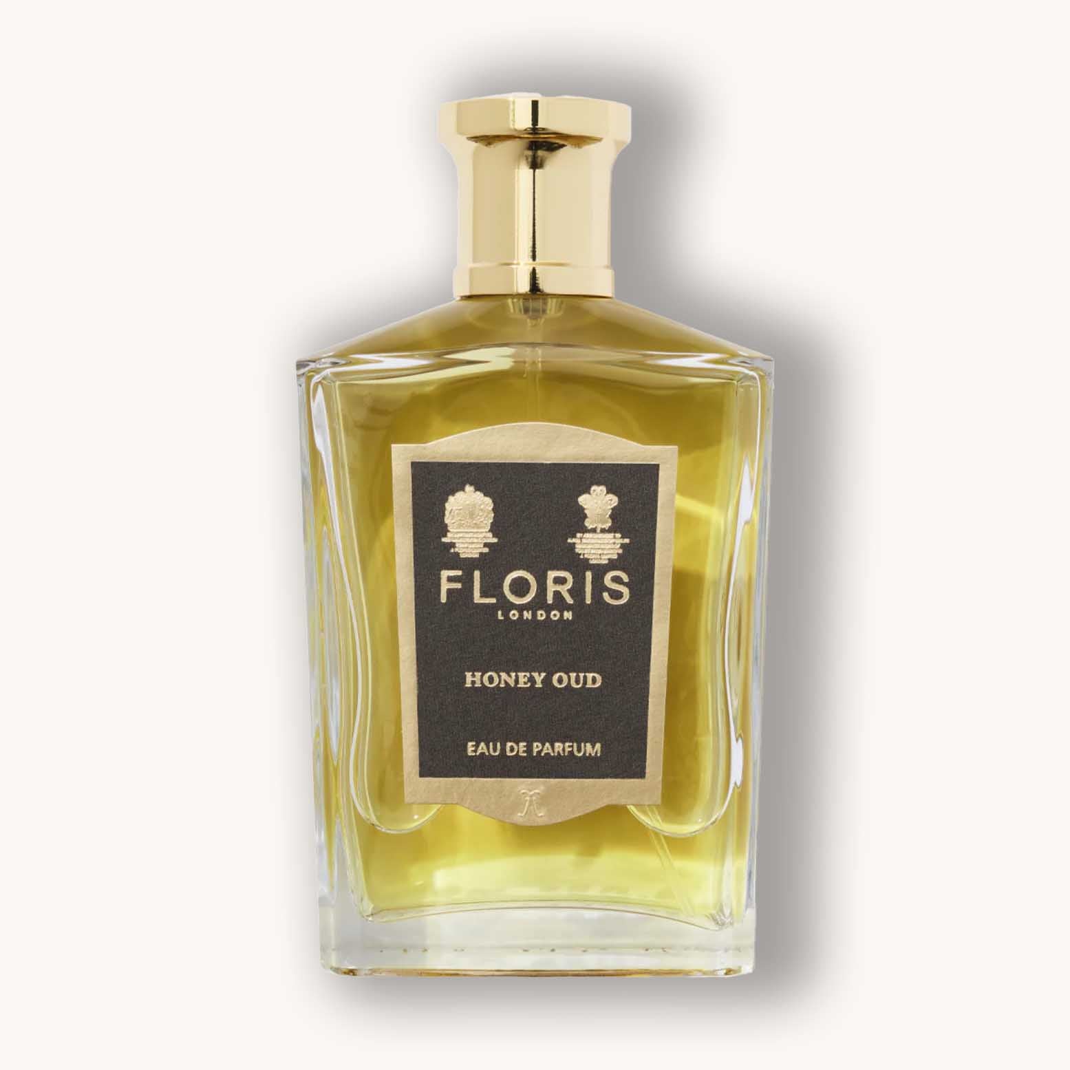 Alt text: A frosted glass bottle of Floris London Honey Oud, showcasing an elegant design with a gold cap and a black label that reads "FLORIS HONEY OUD Eau de Parfum." The liquid inside is a warm honey hue.