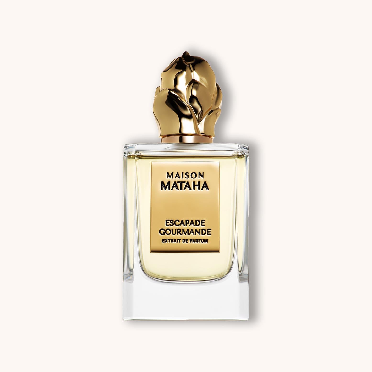 Flacon van Maison Mataha Escapade Gourmande Extrait de Parfum met gouden bloemvormige dop en elegante vierkante transparante glazen fles.