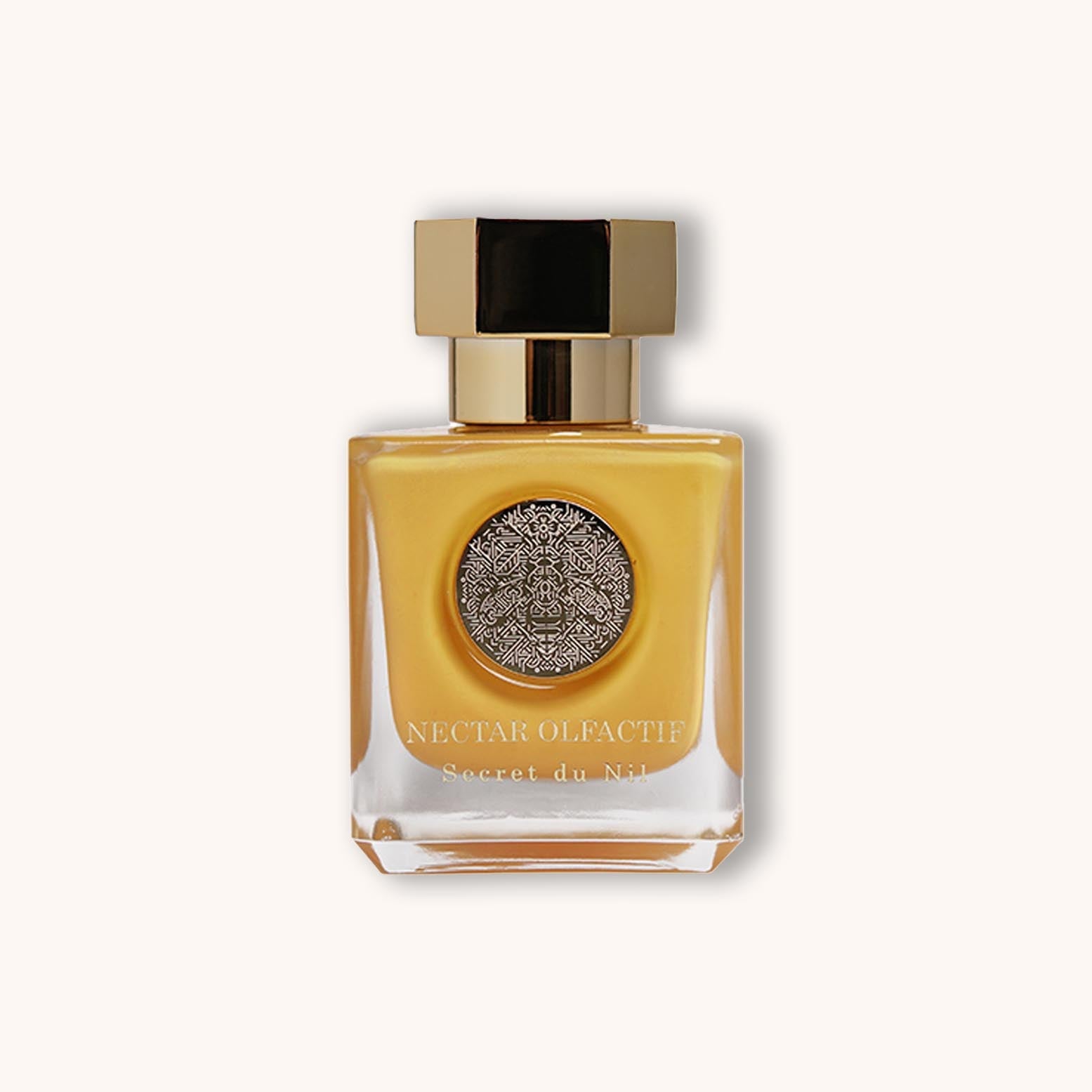 Alt text: A stylish glass bottle of Nectar Olfactif Secret du Nil perfume, featuring a gold and black cap and an ornate embossed emblem on the front, surrounded by a soft, neutral background.